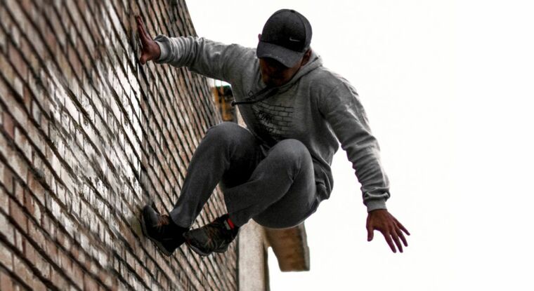 Junger Mann im Sprung an Mauer